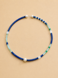 Load image into Gallery viewer, A beaded necklace with alternating strands of deep blue beads, light aqua beads, white translucent beads, and a single white pearl, displayed on a solid beige background.