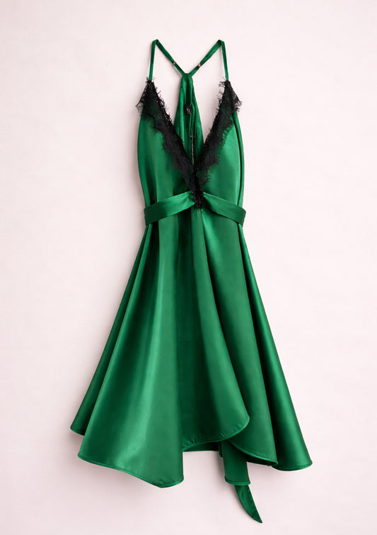 Green satin dress with black lace details on a light pink background