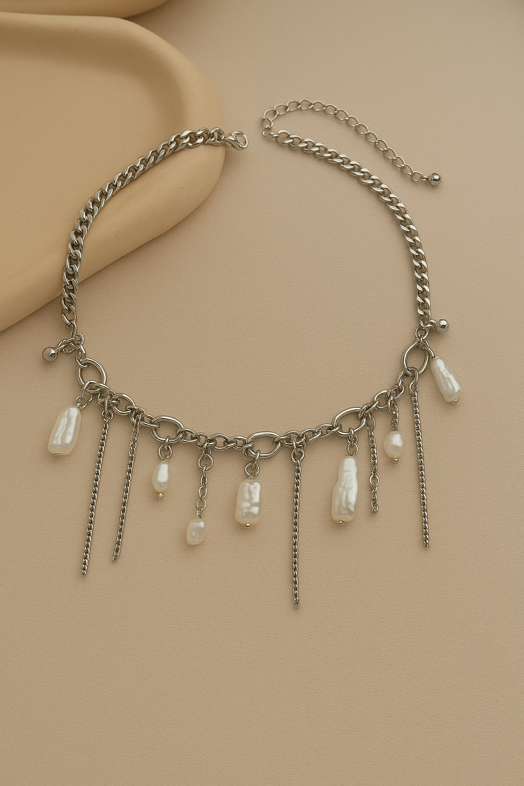 Necklace with chain and pearl-like pendants on a beige background