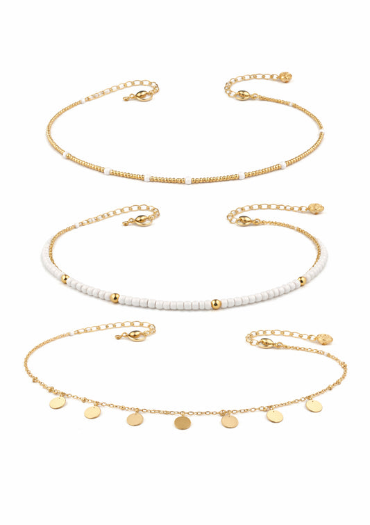 Set of three gold necklaces with different designs on a white background