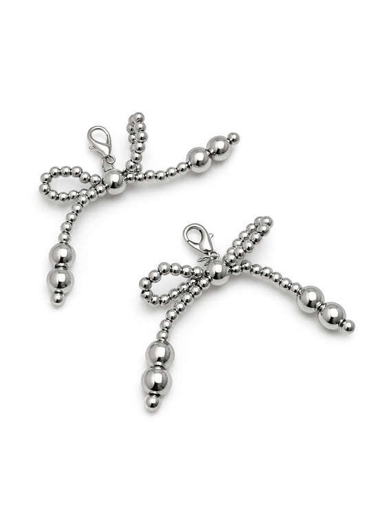 Silver bow-shaped shoe charm on a white background