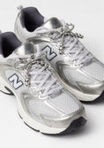 Заредете изображението в програмата за преглед на галерия, Silver New Balance sneakers with decorative bow-shaped shoe charm on a white background