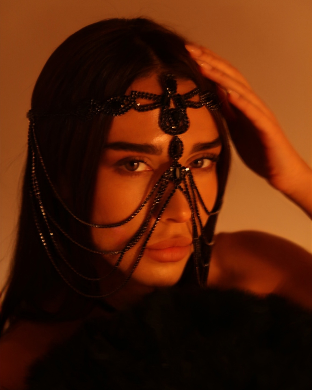 Person wearing a decorative headpiece with a warm-toned background