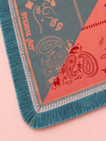 Load image into Gallery viewer, A close-up of a patterned textile or rug corner with teal fringe, a muted blue-gray field, coral pink sections, and ornate paisley and floral motifs. The words 'STAYAWAY' are printed vertically on the blue-gray section.