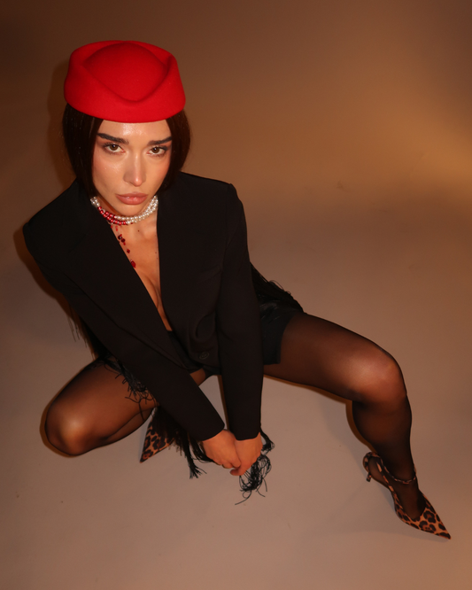 Person wearing a red beret and black outfit on a plain background