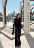 Woman in a black outfit standing in front of a pool area with buildings in the background