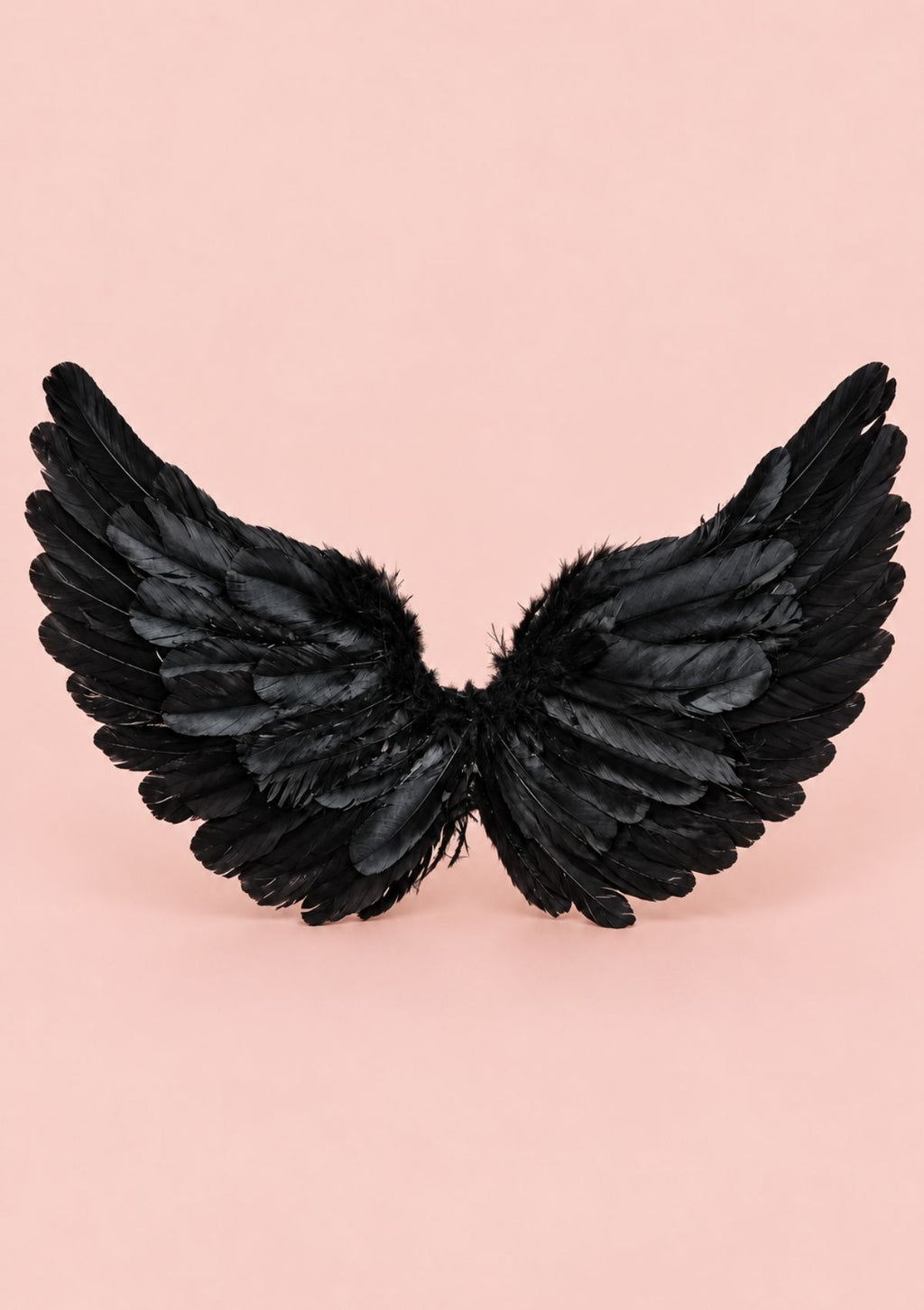 Black feather angel wings accessory displayed against a solid light pink background.