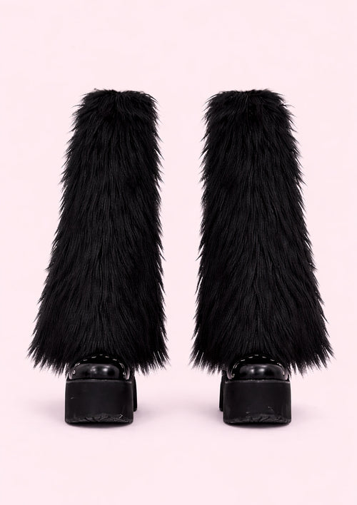 Black furry leg warmers on a light pink background