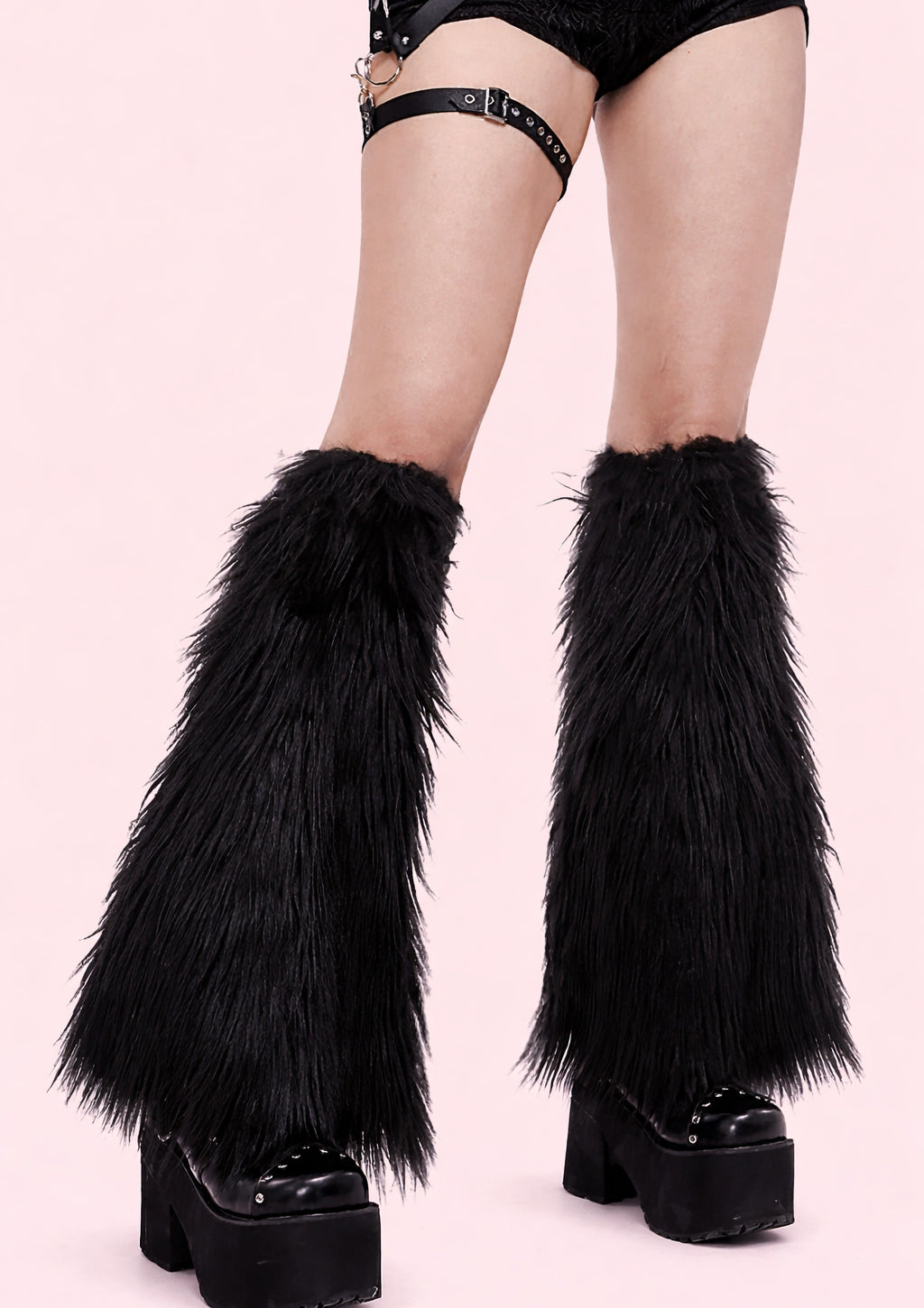 Black furry leg warmers worn with platform shoes on a pink background