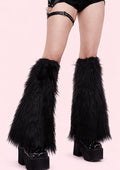 Black furry leg warmers worn with platform shoes on a pink background