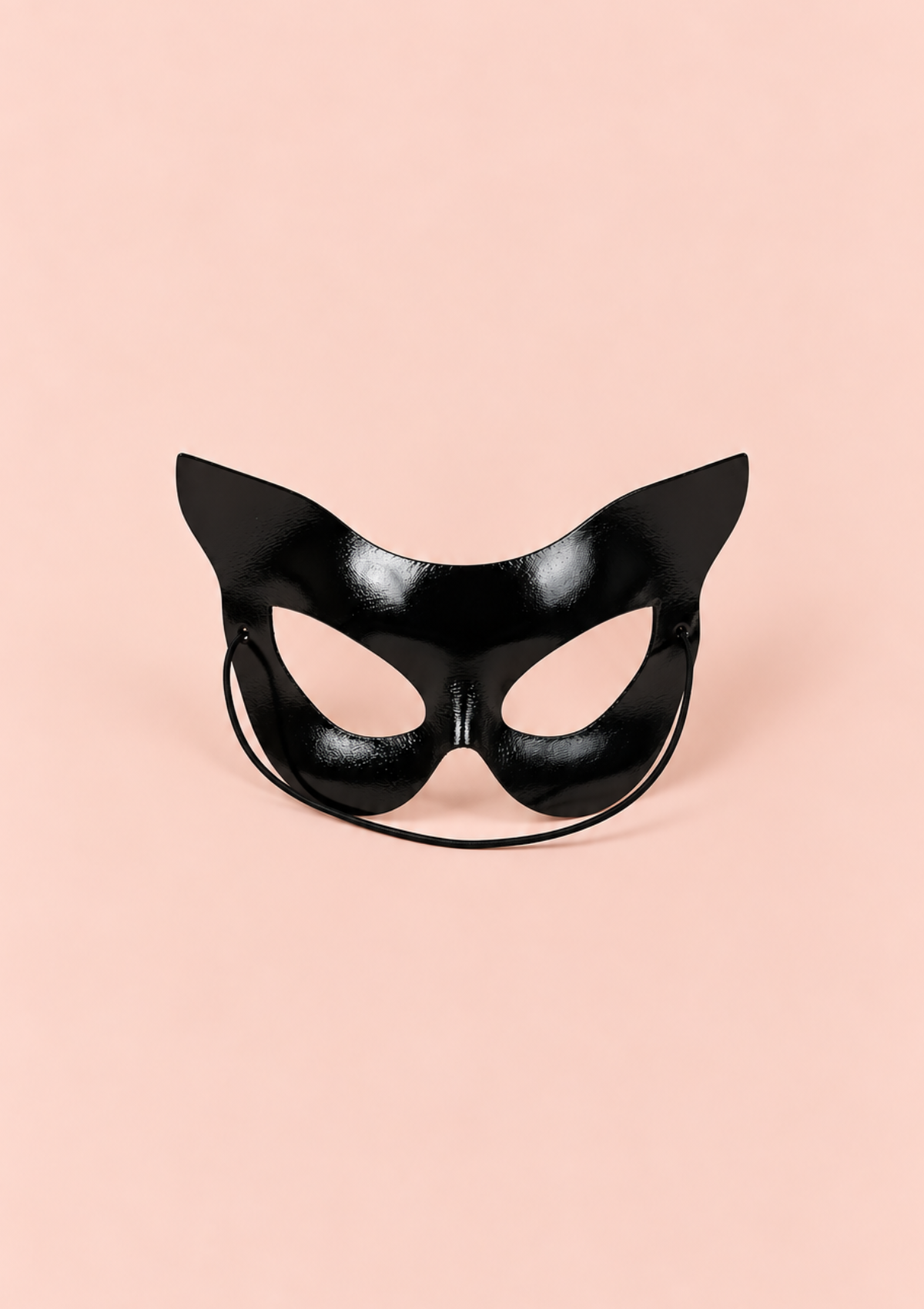 A glossy black cat mask with pointed ears and an elastic strap, centered on a solid pale pink background.