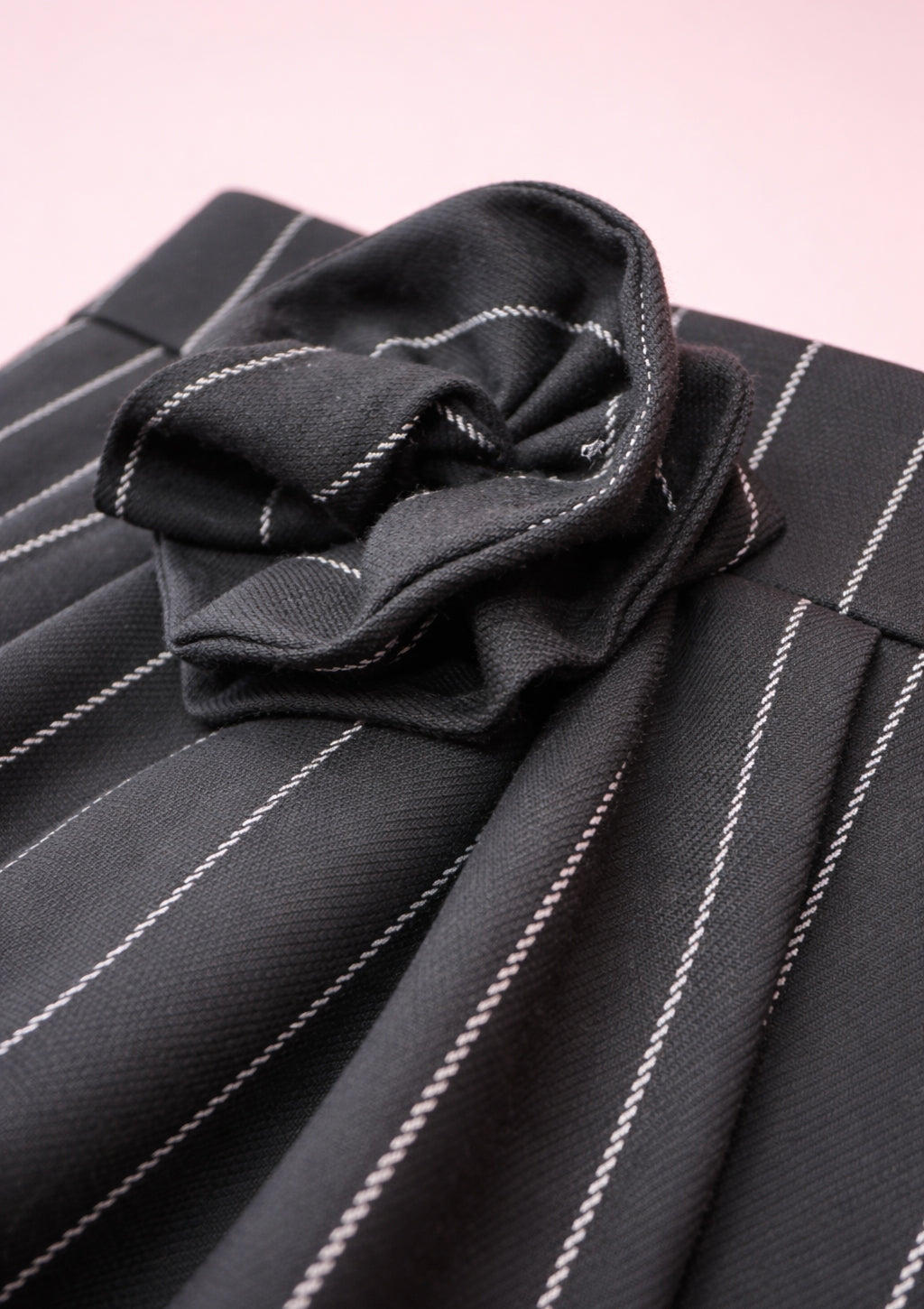 Black pinstripe skirt with a flower detail on a pink background