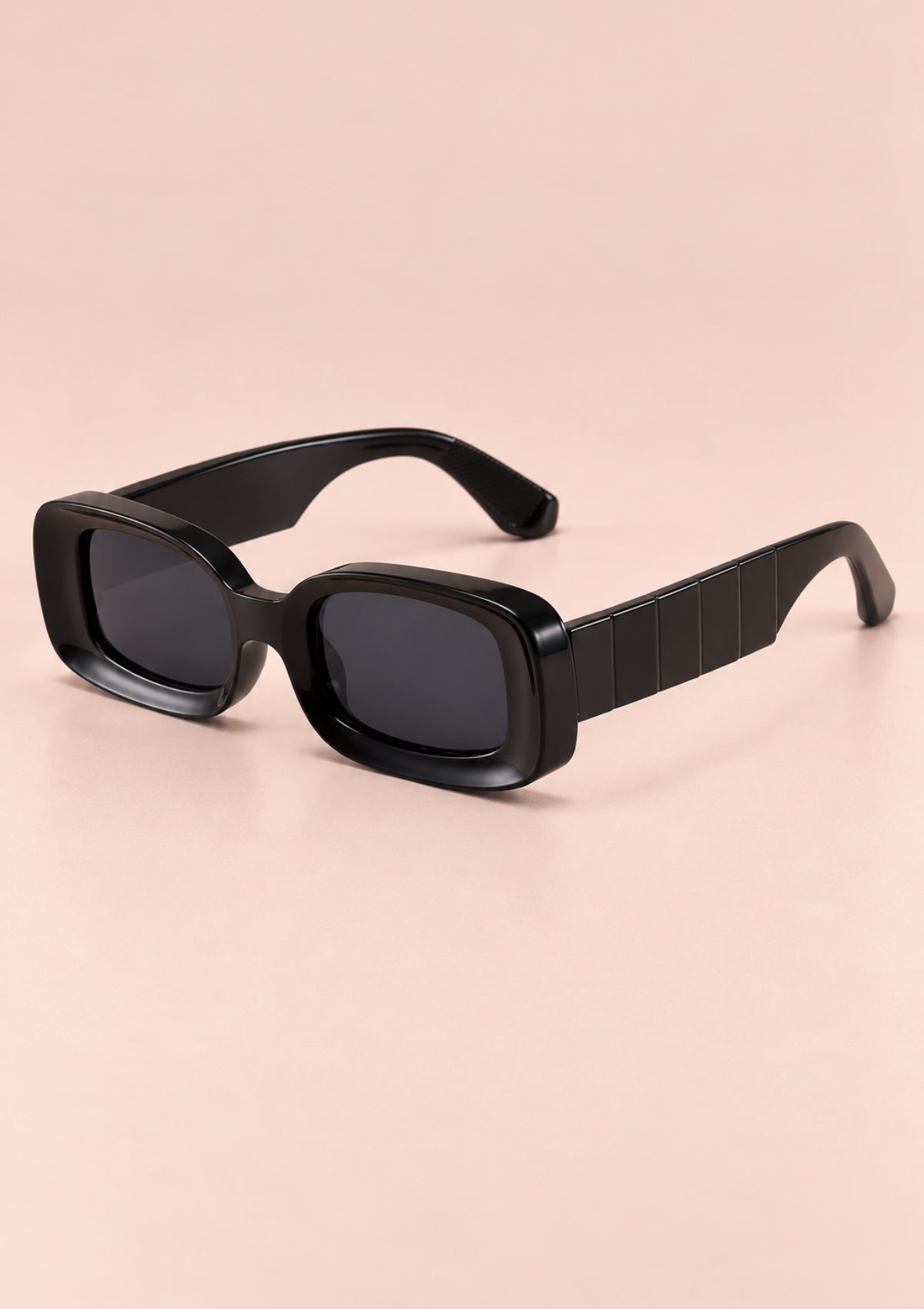 Black oversized square sunglasses with thick textured temple arms, shown on a solid pale pink background.