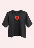 Black t-shirt with a red heart-shaped patch on a light pink background