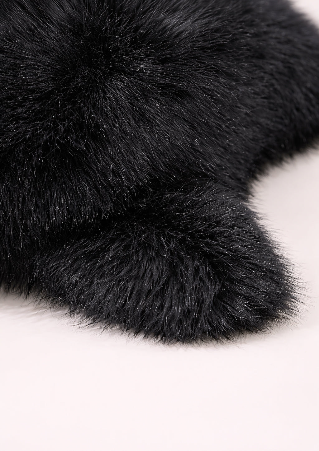 Close-up of black faux fur hat on a light background