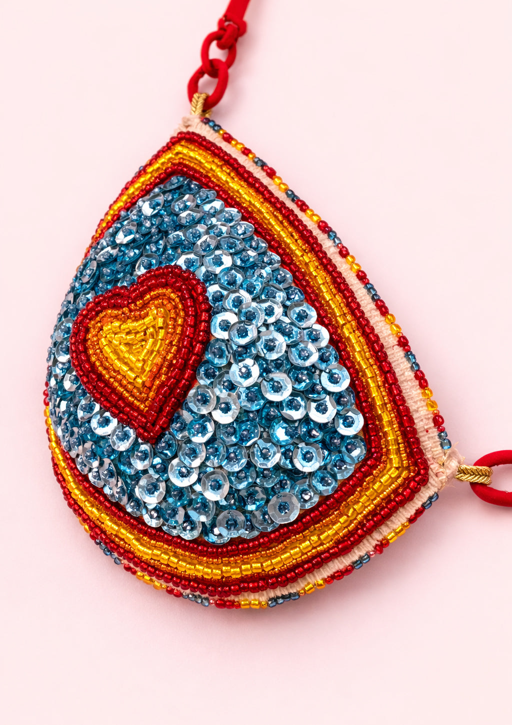 Colorful beaded top with a heart design on a pink background