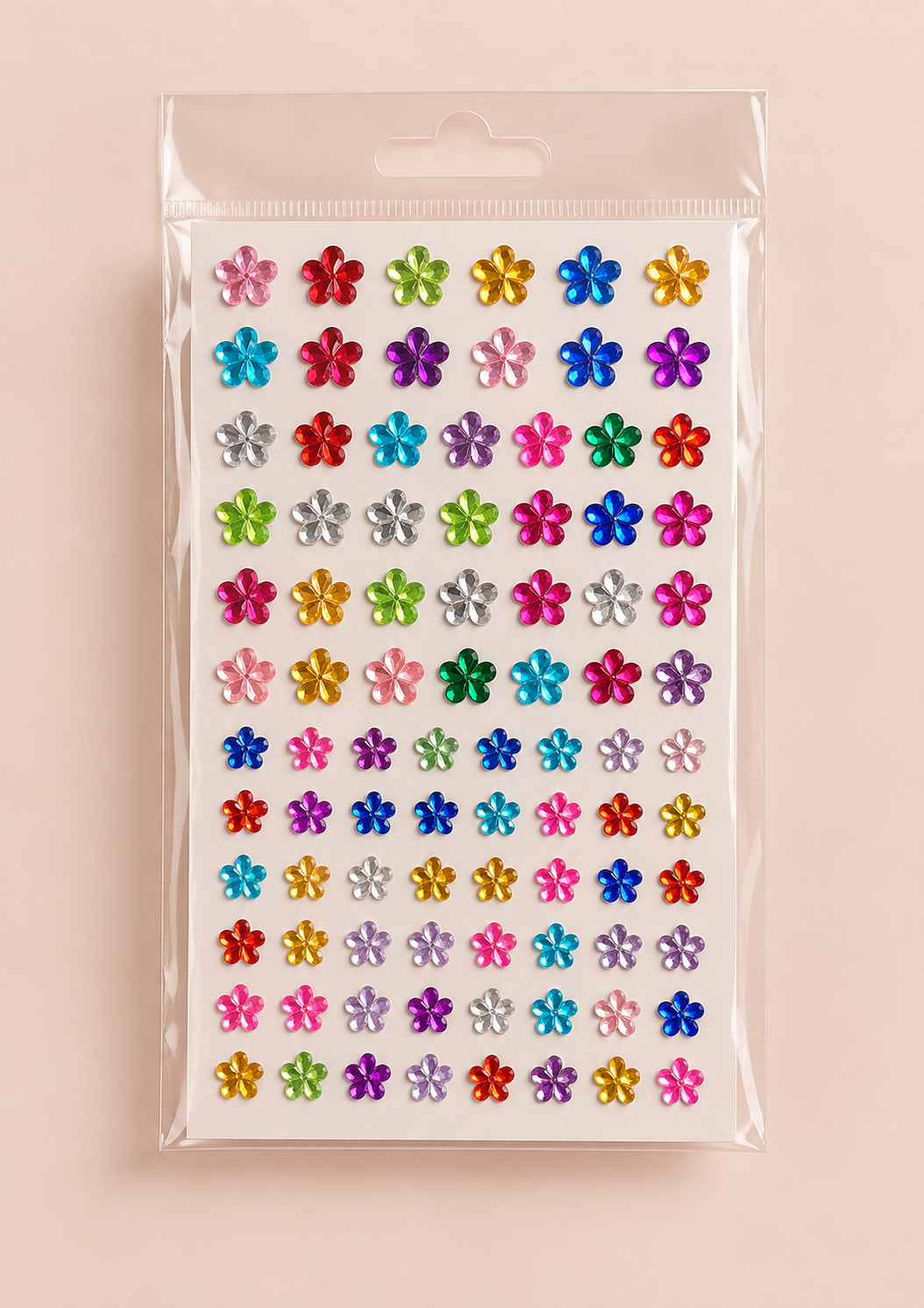 A sheet of small, colorful flower-shaped embellishments in a clear plastic hanging bag, displayed against a solid pale pink background.