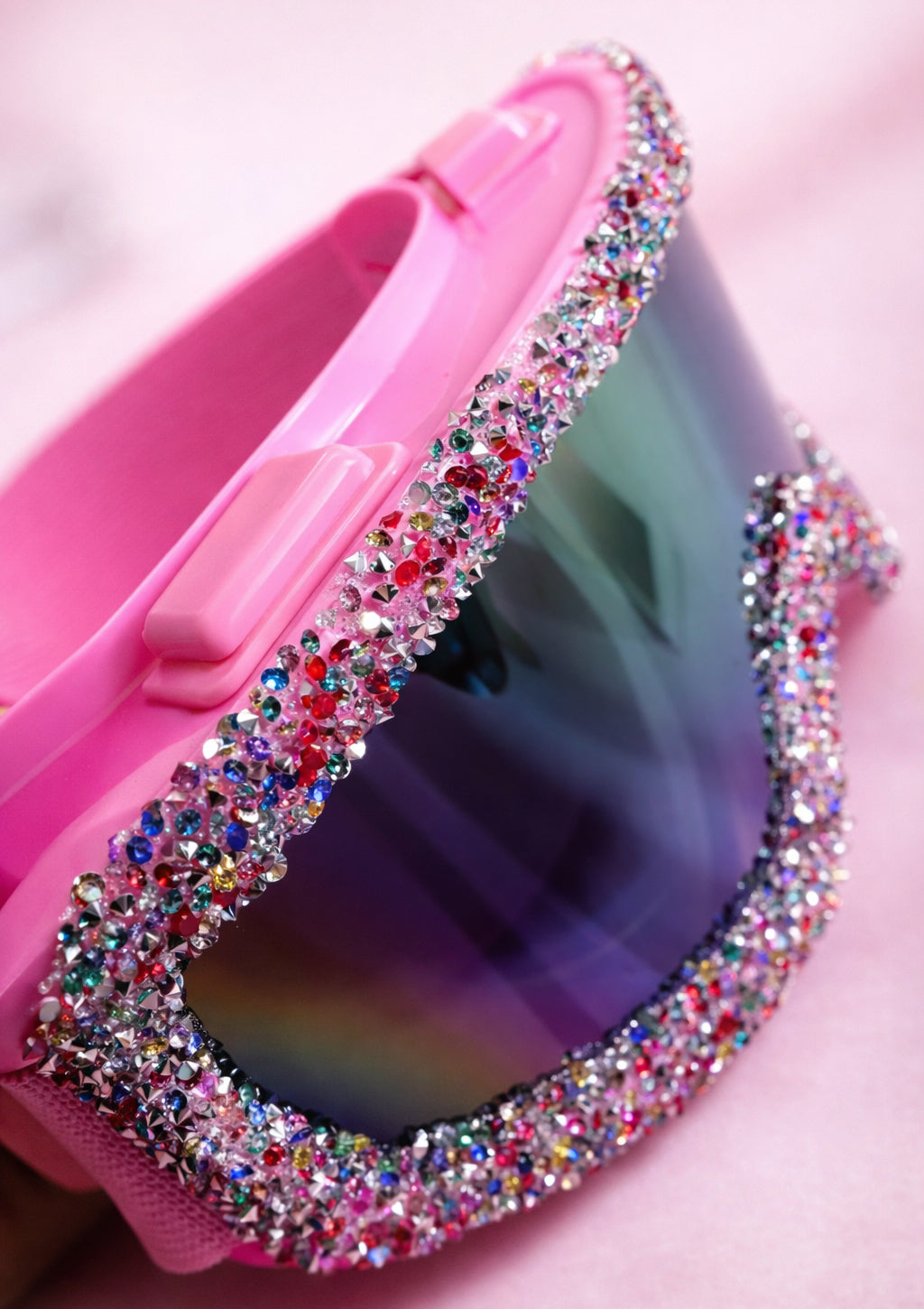 Pink sunglasses with colorful gemstones on a pink background