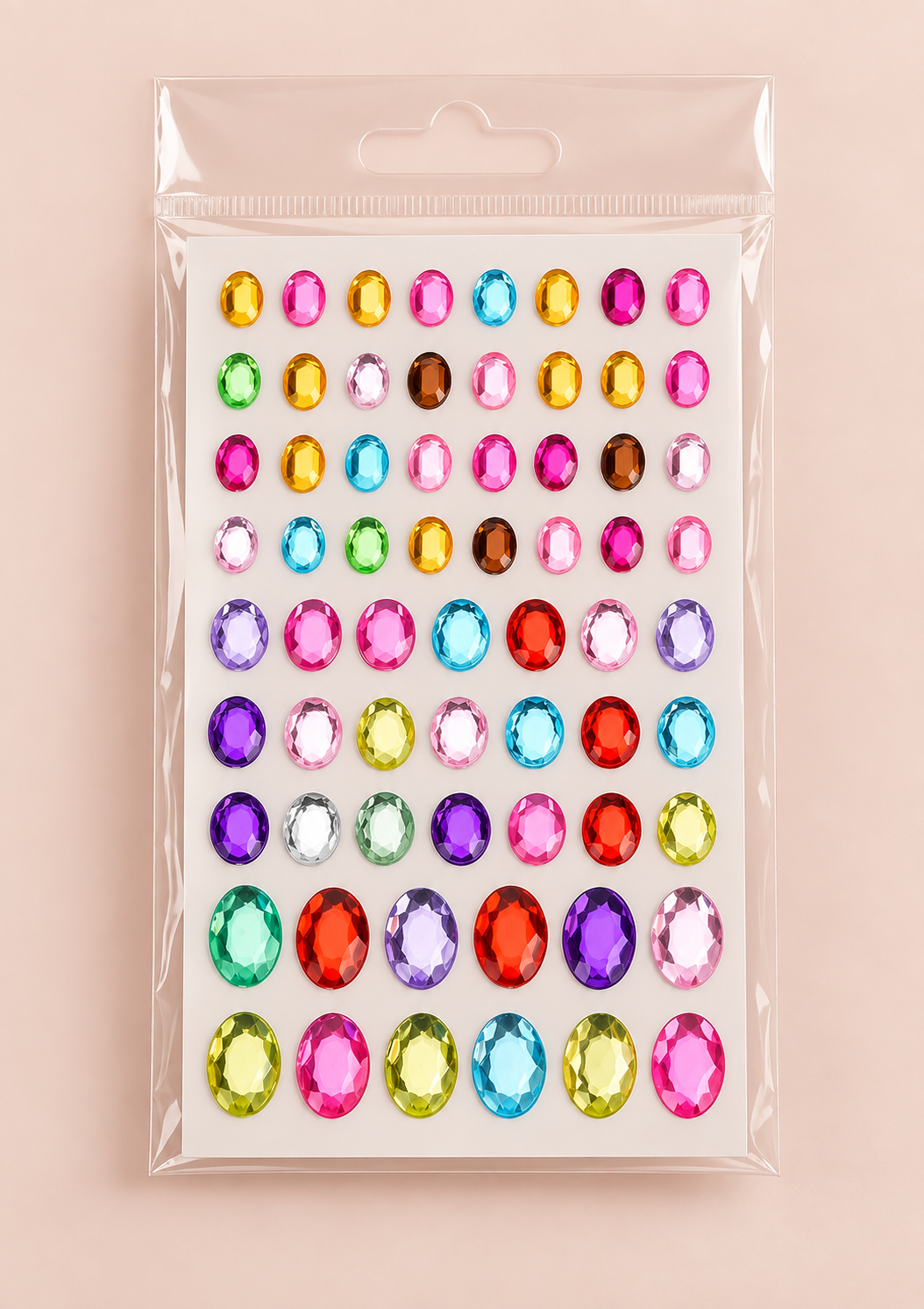 A package of colorful oval rhinestone stickers arranged in a grid on a clear plastic backing, photographed against a soft pink background.