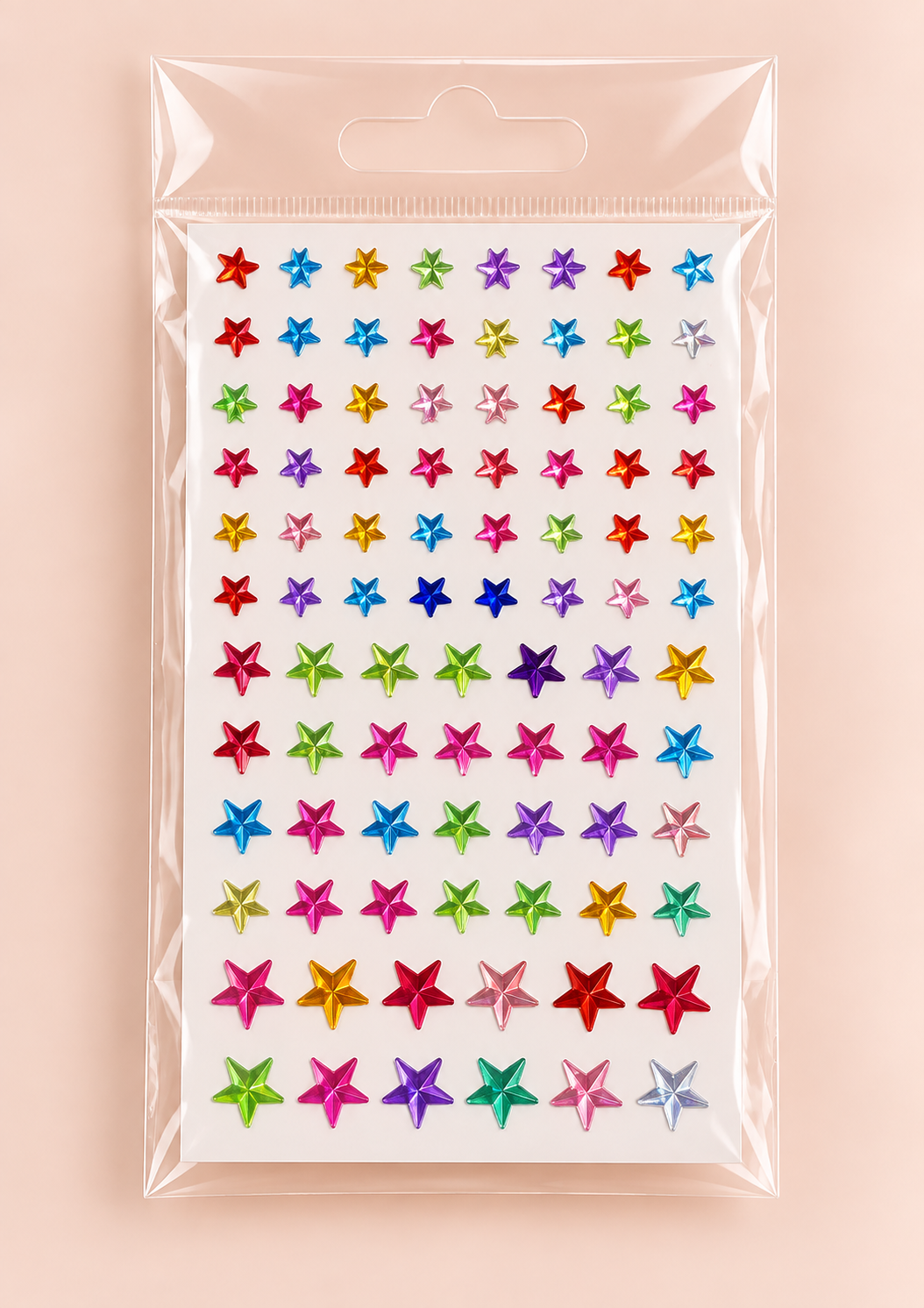 A sheet of colorful star-shaped rhinestones in a clear plastic hanging bag, set against a solid pale pink background.