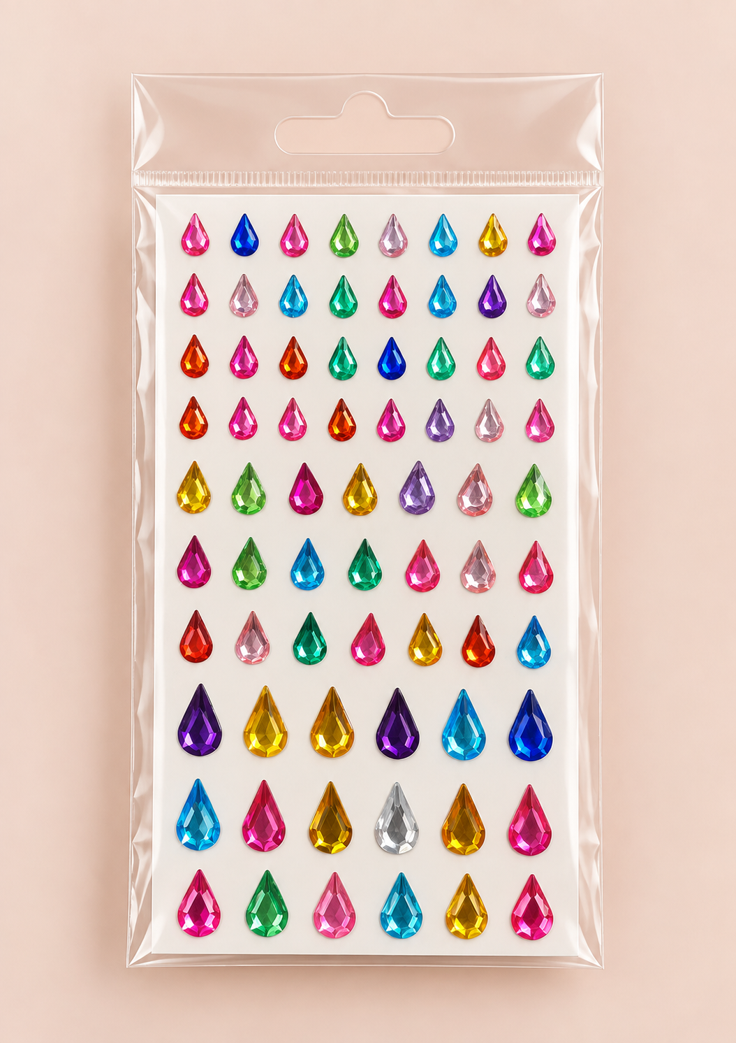 A sheet of colorful teardrop-shaped rhinestones in a clear plastic hanging bag, set against a solid pale pink background.