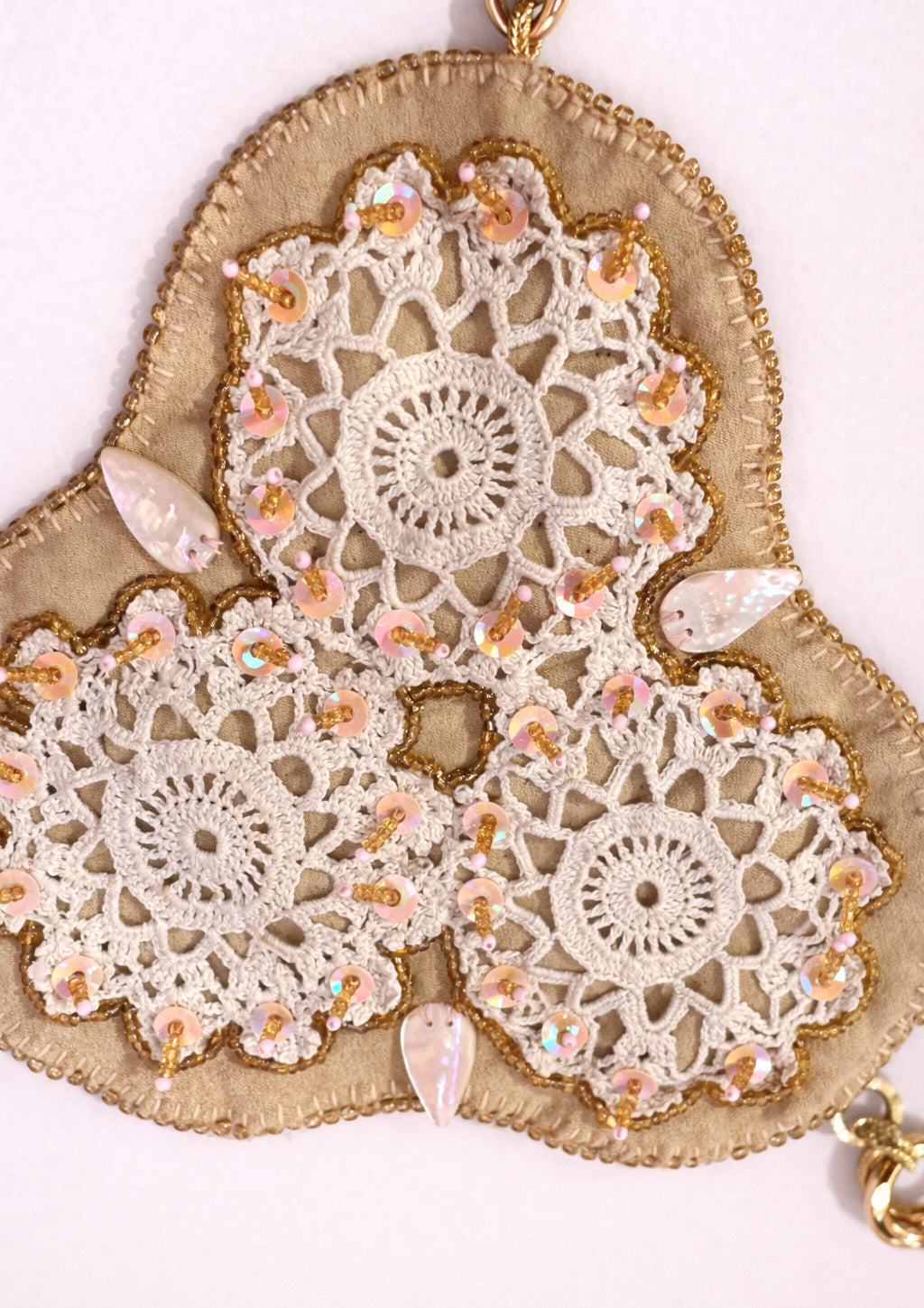 Decorative heart-shaped top with crocheted doilies and seashells on a white background