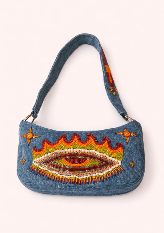 Denim handbag with colorful eye design on a white background