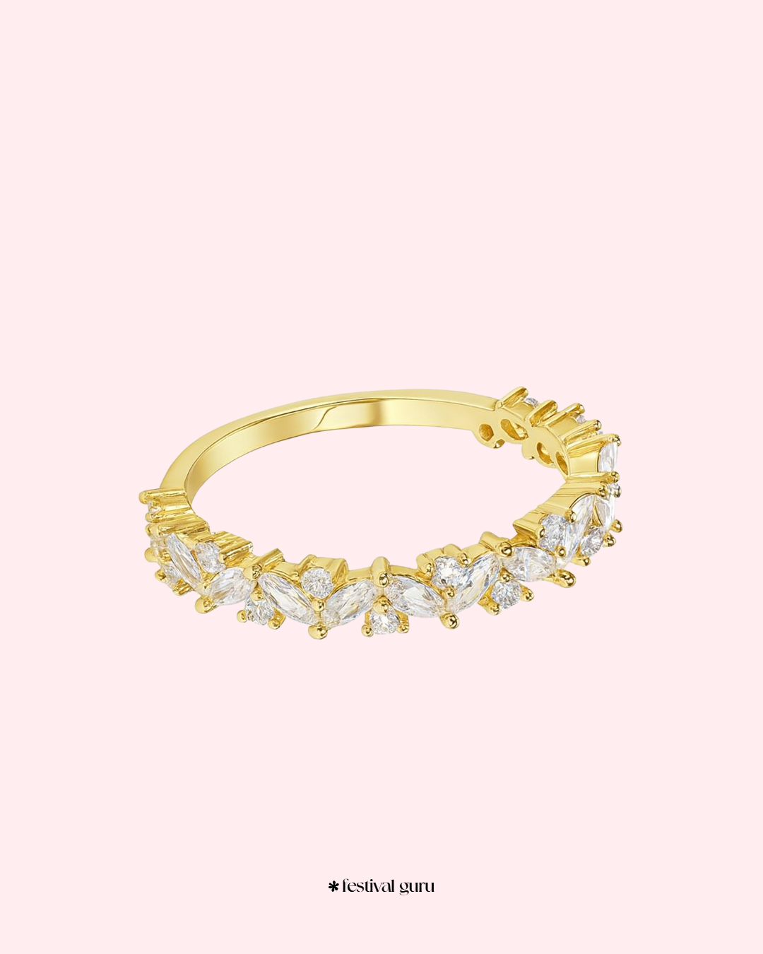Gold ring with diamond-like stones on a light pink background