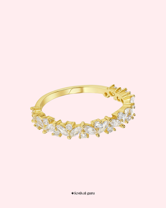 Gold ring with diamond-like stones on a light pink background