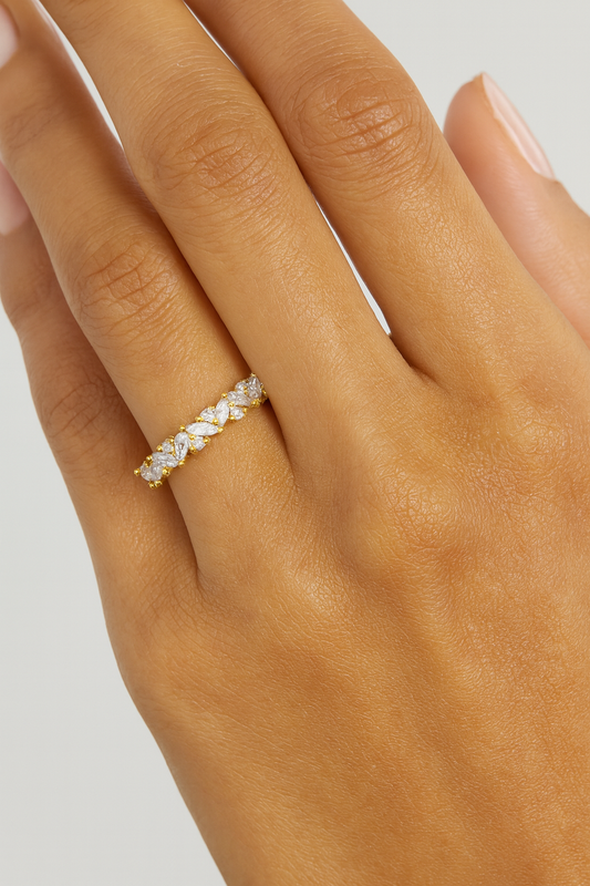 Gold ring with small stones on a hand against a neutral background