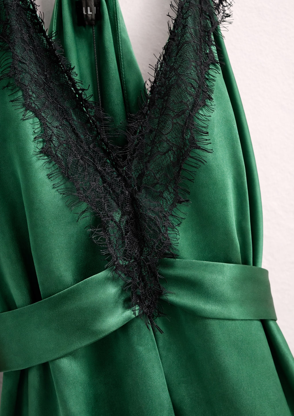 Green dress with black lace detailing on a plain background