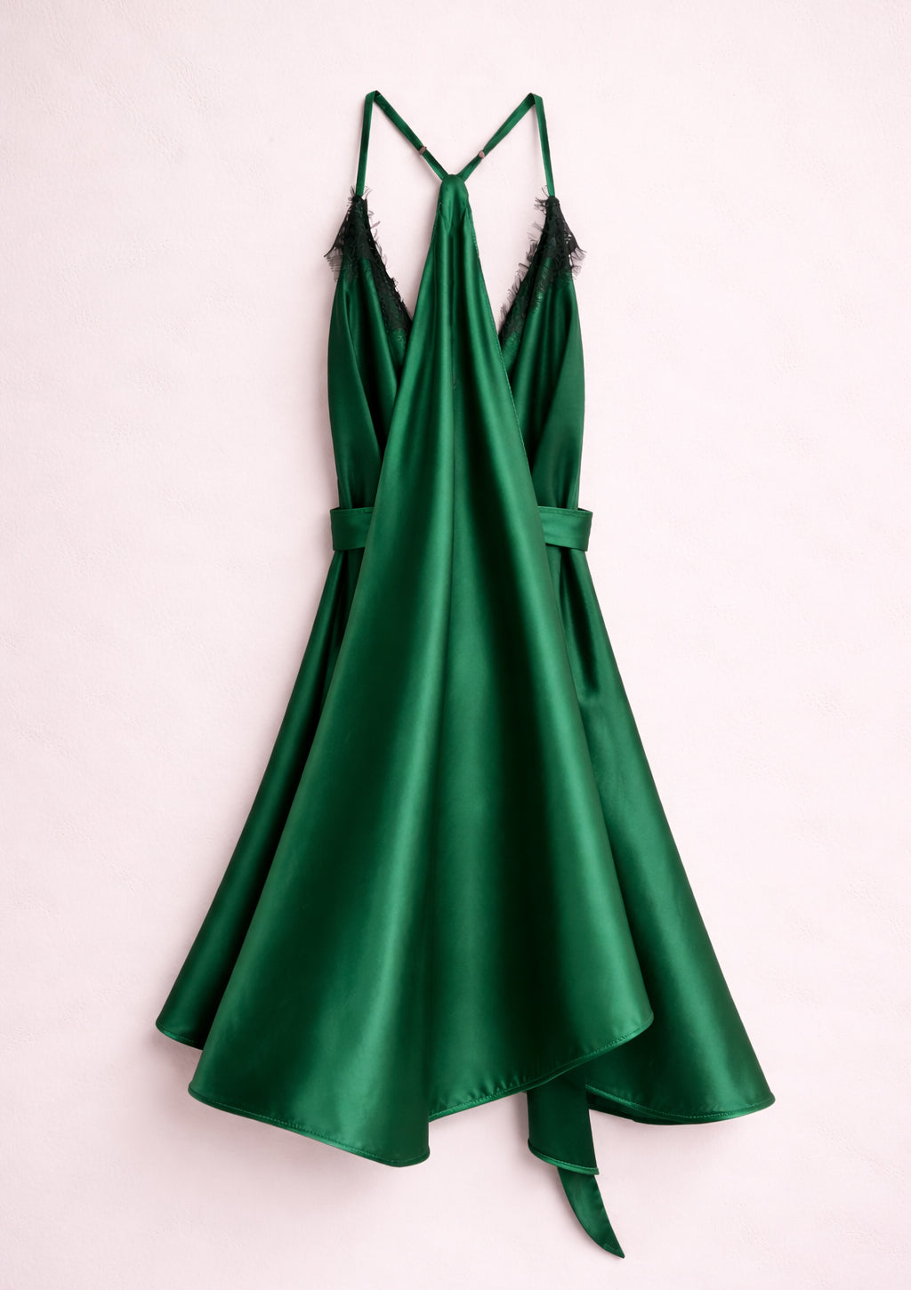 Green satin dress with thin straps on a light pink background