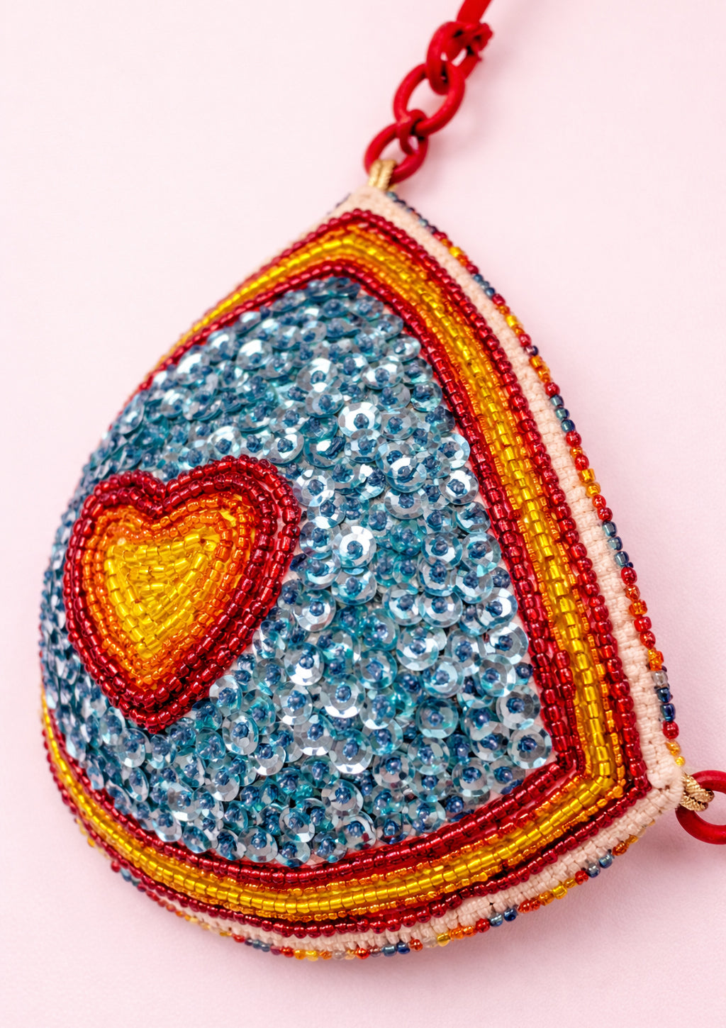 Heart-shaped beaded bra top with red string on a pink background