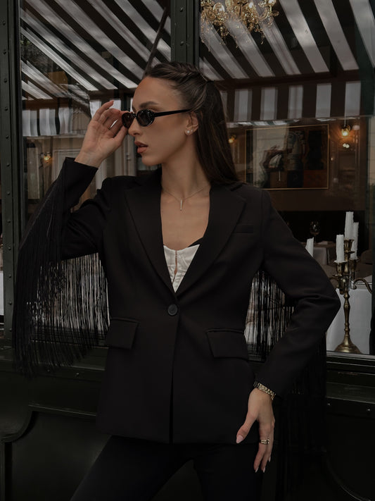 Woman in a black suit adjusting sunglasses in an elegant interior setting