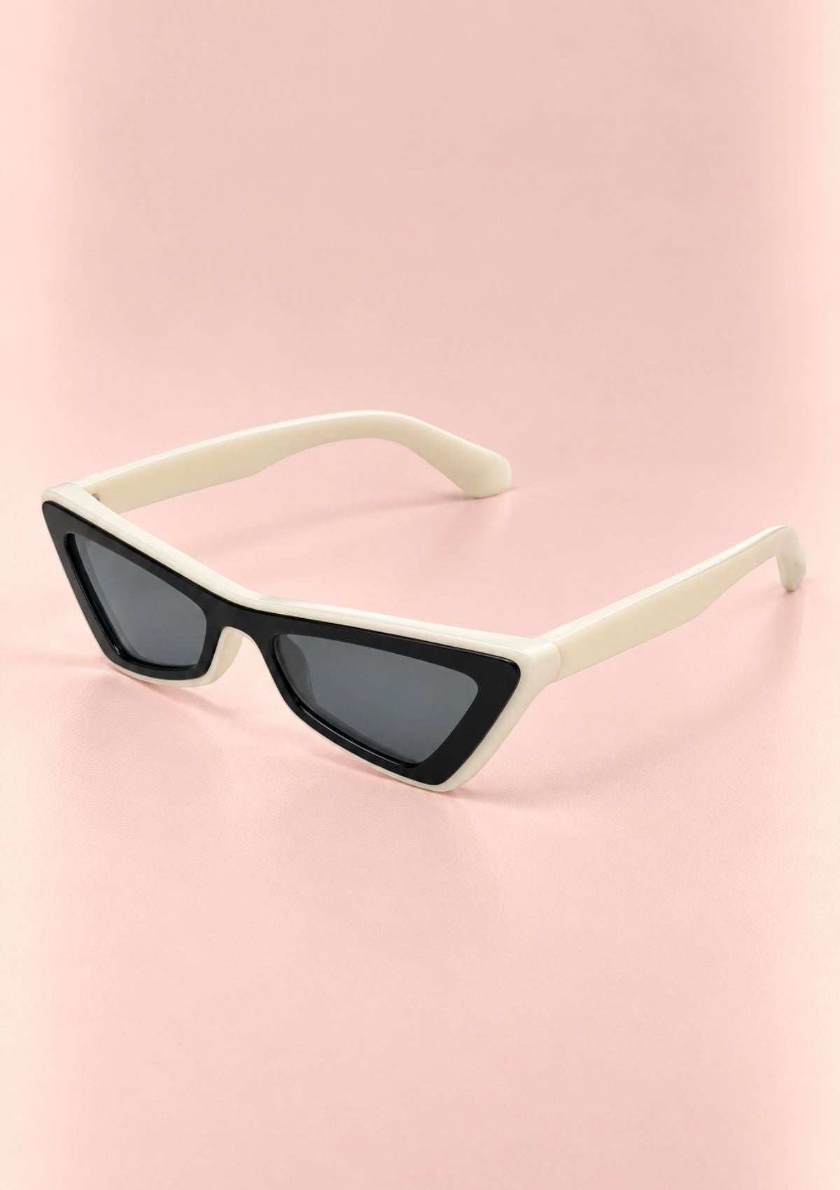 Triangular cat-eye sunglasses with cream-colored frames and dark gray lenses, displayed on a soft pink background.