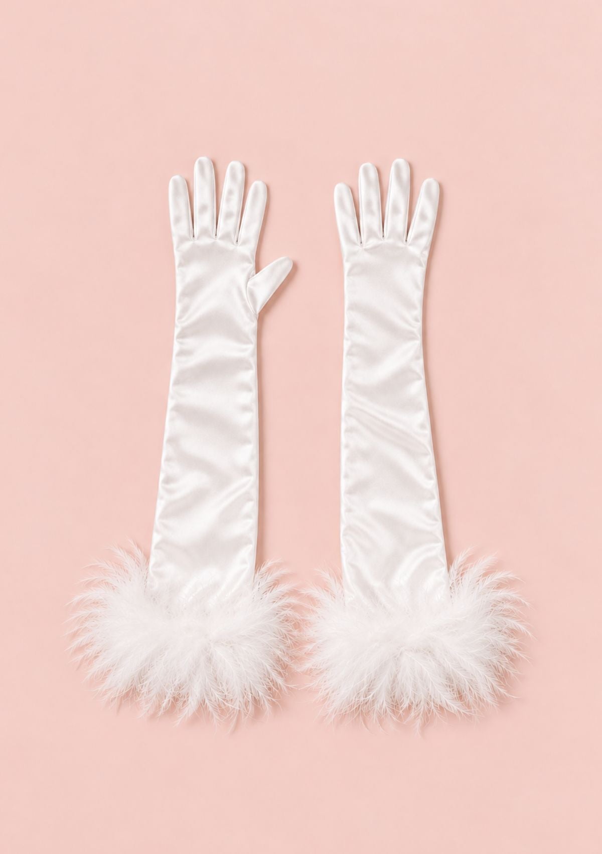 A pair of long white satin opera gloves with fluffy white feather trim at the cuffs, displayed flat against a solid pale pink background.