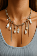 Necklace with pearls and chain drops on a person wearing a gray tank top.