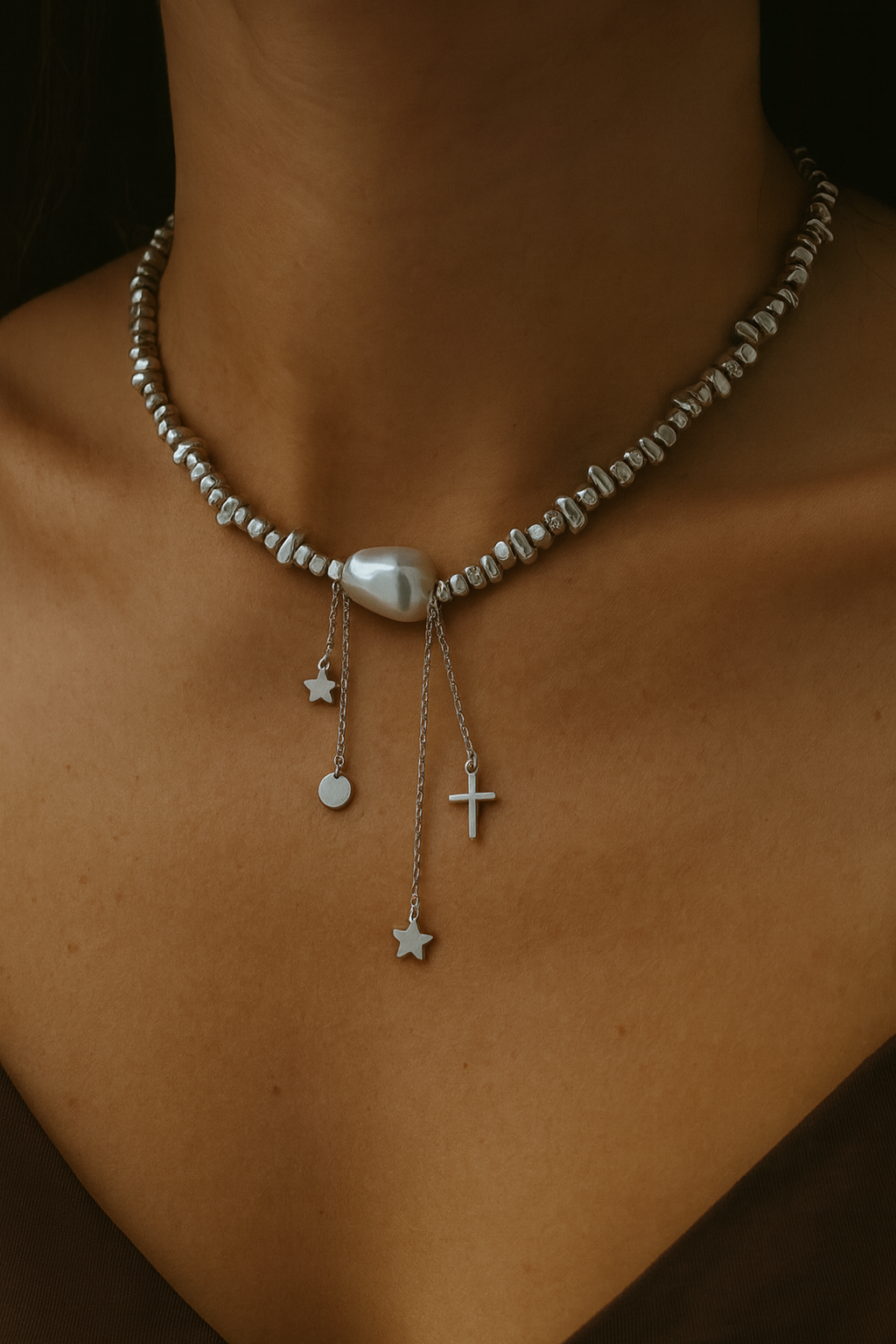 Necklace with pearls and charms on a person's neck against a dark background