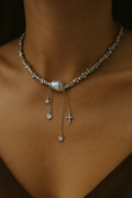 Necklace with pearls and charms on a person's neck against a dark background