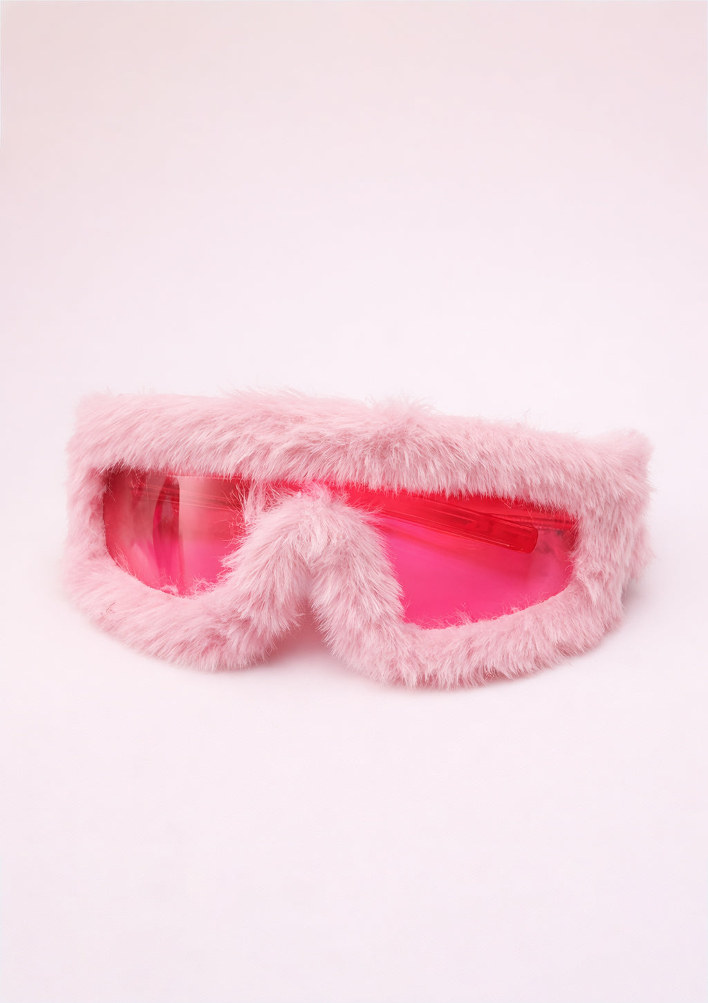 Pink fluffy eye mask on a light pink background