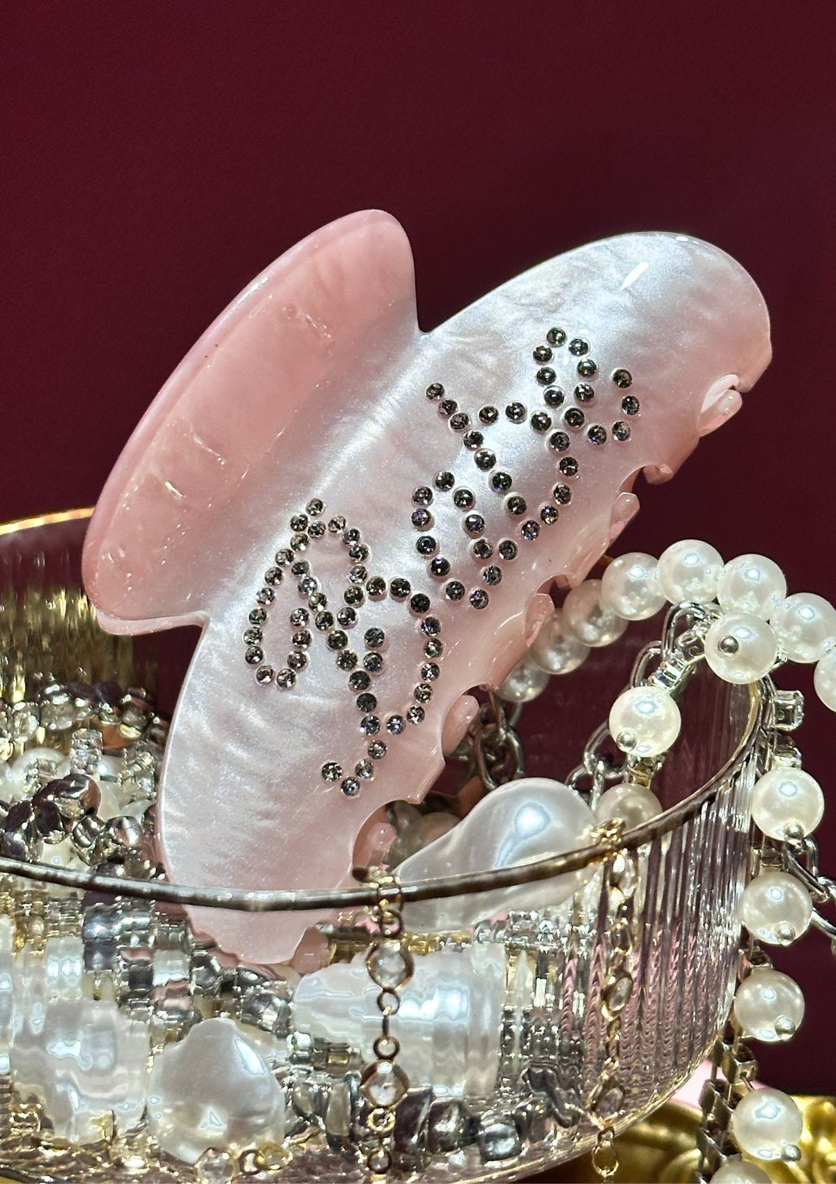 Decorative hair clip with rhinestones and pearls on a red background
