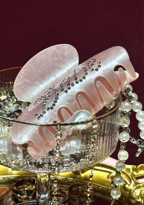 Pink hair clip with decorative elements on a red background