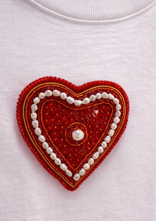 Red heart-shaped patch with beads on a white background