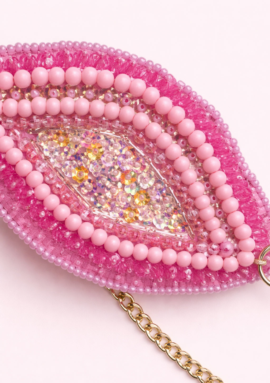 Pink beaded bra with a gold chain on a white background