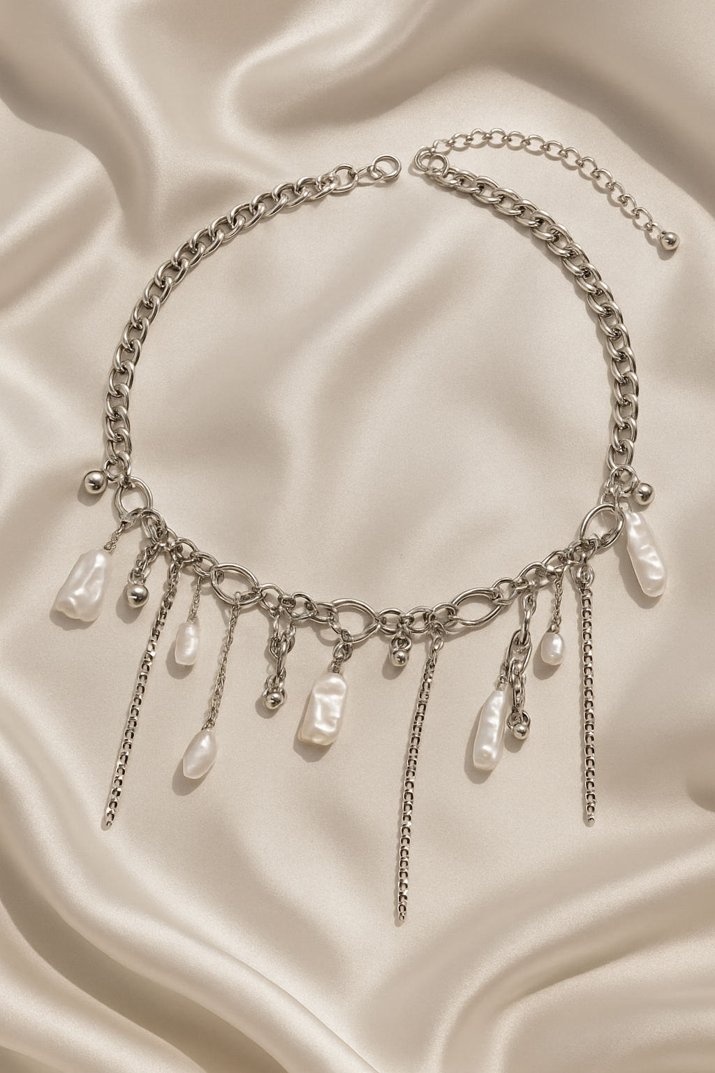 Silver necklace with pearl-like beads on a beige fabric background