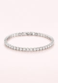 Silver bracelet with clear stones on a light pink background