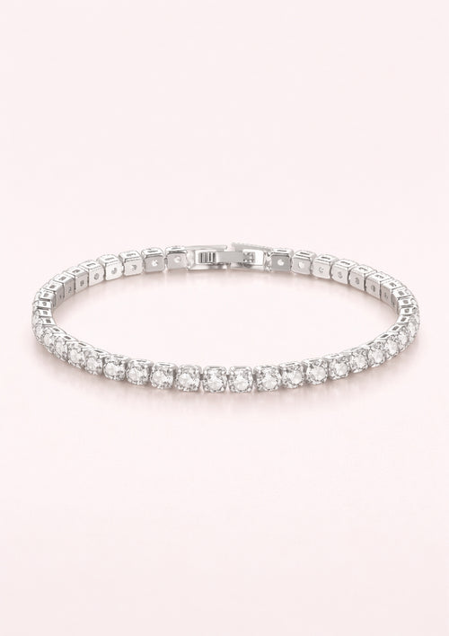 Silver bracelet with clear stones on a light pink background