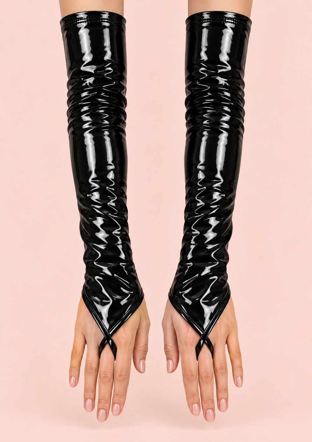 A pair of glossy black patent leather opera gloves worn on hands, featuring a crinkled textured design and a split V-shaped cut at the fingertips, set against a solid pale pink background.