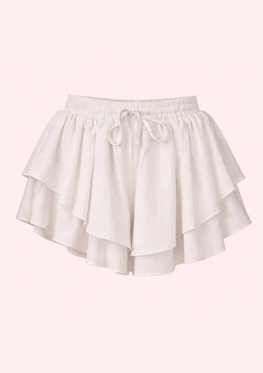 White shorts with ruffled layers on a light pink background