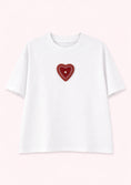 Load image into Gallery viewer, White t-shirt with a red heart-shaped patch on a light pink background
